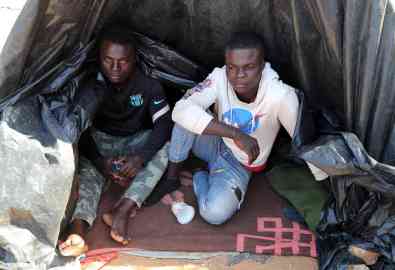 Sub-Saharan African migrants are seen sitting near tents at a camp in Jebeniana, Sfax governorate, Tunisia | Photo: EPA/MOHAMED MESSARA