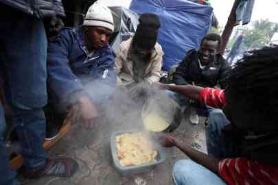 Sub-Saharan African migrants eat at a makeshift camp outside the International Organisation for Migration headquarters in Tunis, Tunisia | Photo: ARCHIVE/EPA/MOHAMED MESSARA
