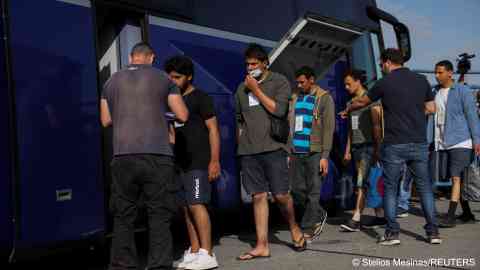 Survivors of a deadly shipwreck after a boat capsized at open sea off Greece, board a bus as they are being transferred to Athens from the port of Kalamata, Greece, June 16, 2023 | Photo: Reuters/Stelios Misinas 
