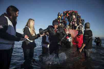 Volunteers welcome migrants disembarking from a boat on the island of Lesbos on December 1, 2015. Photo: Ozge Elif Kizil, Anadolu Agency via AFP
