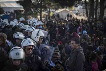 Stranded migrants and refugees stand in front of a Greek police cordon as they try to cross the Greek-Macedonian border near the village of Idomeni, Greece on December 3, 2015 | Photo : AFP