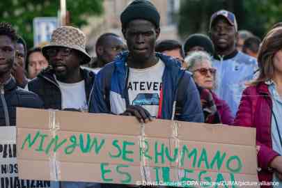 File photo: Demonstrators marched before parliament in 2024 to get the regularization process under way. Now the government has announced that applications will open in April this year. Here a man holds a sign saying 'no human is illegal' | Photo: David Canales/SOPA Images/ZUMA/picture alliance