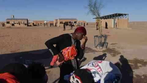 A Malian woman deported from Algeria waits at a water station near the Assamaka transit camp in northern Niger. Photo: Mehdi Chebil