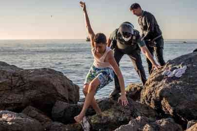 Members of Spain's Guardia Civil accompany a young Moroccan migrant who reached swimming El Tarajal beach in the Spanish city of Ceuta in Morocco | Photo: ARCHIVE/EPA/BRAIS LORENZO