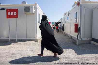 A young woman walking in a Greek camp. | Photo: Nicolas Economou/NurPhoto/picture alliance 