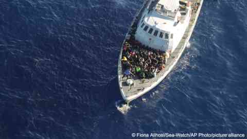 In this handout photo released by German non- governmental organization Sea- Watch on October 25, 2022, migrants sit on the deck of a Libyan coast guard ship after being intercepted while trying to cross the Mediterranean Sea on a rubber boat to Europe | Photo: picture alliance