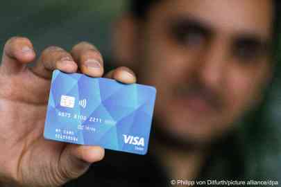 An asylum seeker in Germany holding a payment card (January 2024) | Photo: Philipp von Ditfurth/picture-alliance