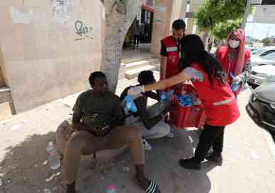 A member of the Tunisian Red Crescent distributing food for Sub-Saharan African migrants in Sfax, in the south of Tunis, Tunisia | Photo: ARCHIVE/EPA/MOHAMED MESSARA