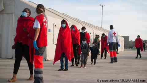 COVID-19 shutdowns worldwide resulted in a temporary fall in arrival numbers, but it did not put a stop to migration and refugee movements. In the picture, a group of sub-Saharan migrants wearing face masks as a precaution, seen in Malaga, Spain, after being rescued by the Spanish coast guard, September 11, 2020 | Photo: Jesus Merida/SOPA Images via ZUMA Wire