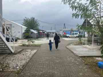 Asra, 3, holds Jasmina’s hand, in the transit center of Vinojug, in southern North Macedonia, near the Greek border. Jasmina is a worker for the NGO Legis. Guevgueliya, North Macedonia, October 2025 | Photo: InfoMigrants