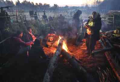 AP - Ramil Nasibulin | Migrants from the Middle East and elsewhere warm up by a fire at the Belarus-Poland border near Grodno, Belarus,10 November 2021. 