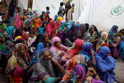 Women displaced because of the floods wait to receive food handouts while taking refuge in a camp, in Sehwan, Pakistan, September 30, 2022 | Photo: Akhtar Soomro/Reuters