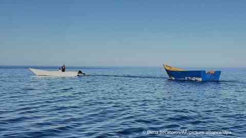 File photo: A boat used by migrants to cross the Mediterranean Sea is towed from Tripiti  beach to the port of Gavdos, Greece, July 7, 2025 after hundreds were rescued near the island and the island of Crete | Photo: AP Photo/Elena Becatoros/ picture alliance