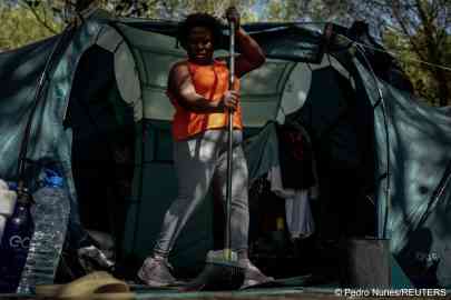 Marcia Leandro, 43, from Rio de Janeiro, Brazil, cleans her tent at the improvised campsite in a field where she lives in Carcavelos, in Cascais, Portugal, October 11, 2023 | Photo: Pedro Nunes / Reuters
