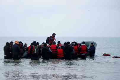Migrants attempting to board an inflatable boat to cross the English Channel | Photo: Reuters