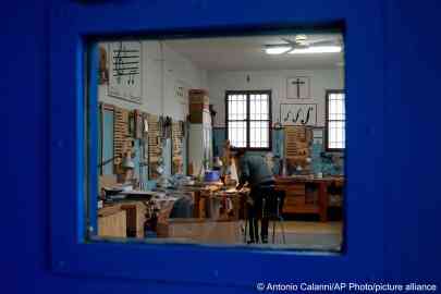 At Milan's Opera maximum security prison an inmate works on the top plate of a violin made from the wood of a wrecked migrants' boat in the prison's lab | Photo: Antonio Calanni / AP Photo