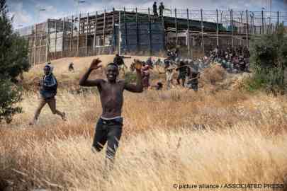 From file: Migrants are seen running away from the border fence after crossing onto the Spanish enclave of Melilla on June 24, 2022 | Photo: Javier Bernardo/AP/picture-alliance
