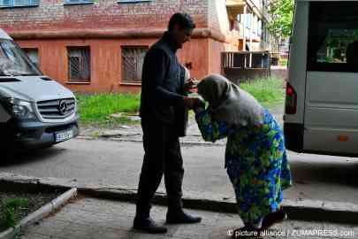 From file: A man is seen helping an old woman to get on an evacuation bus from Kramatorsk to Dnipro, Ukrain, on May 9, 2022 | 