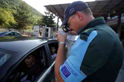 A member of the European Border and Coast Guard Agency Frontex is seen checking documents at the  border point into Albania on July 23, 2019 | Photo: REUTERS/Florion Goga