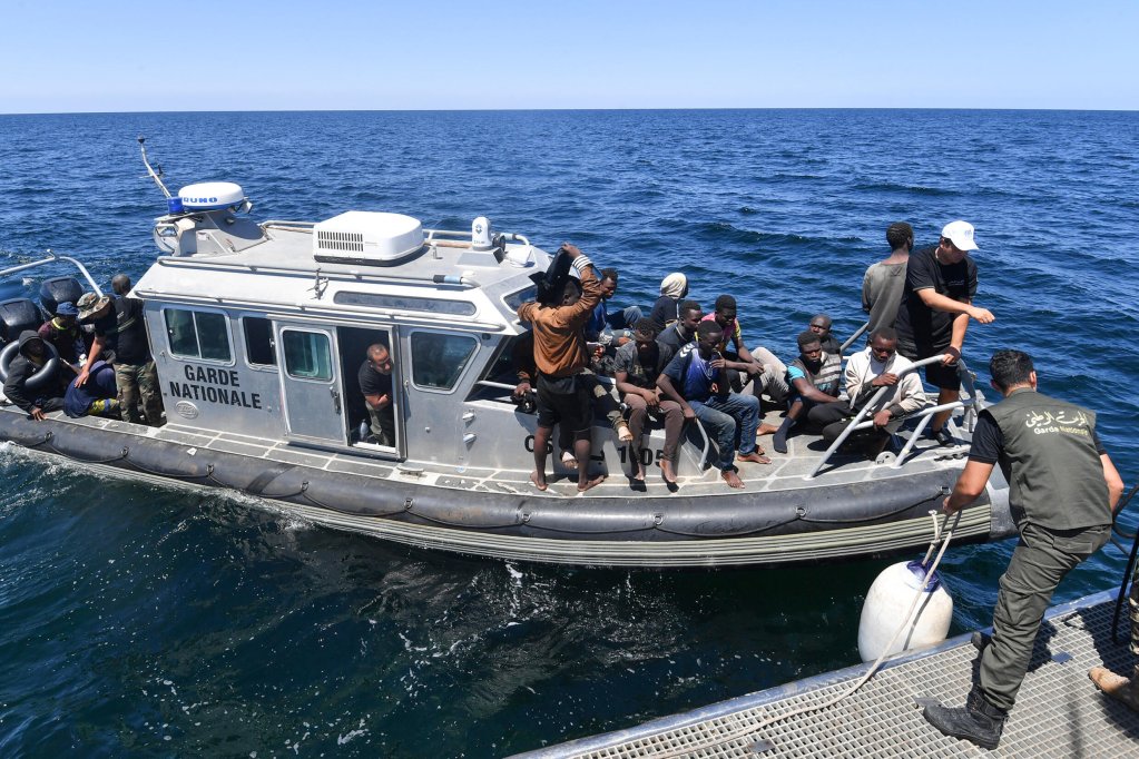 © AFP | Migrants of African origin trying to flee to Europe are transferred from a small boat belonging to the Tunisian coast guard onto a larger vessel, at sea between Tunisia and Italy, on August 10, 2023.