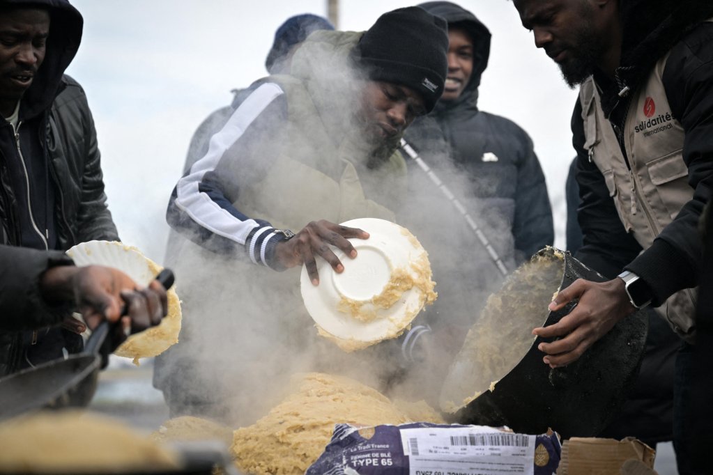 Des migrants soudanais préparent un repas dans un camp de migrants, à Ouistreham, dans le nord-ouest de la France, le 11 décembre 2023. Crédit : AFP