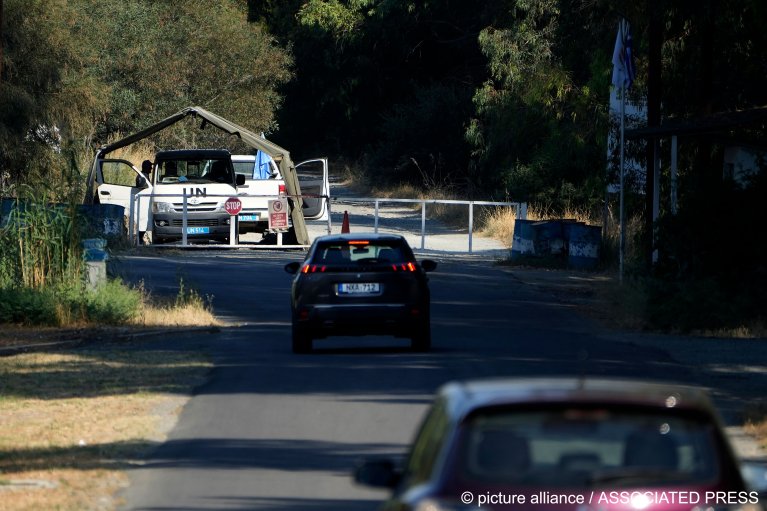 From file: Cars pass U.N peacekeepers as they stand guard inside the U.N buffer zone at the area where some migrants are stranded | Photo: Petros Kardijias / AP Photo / picture alliance