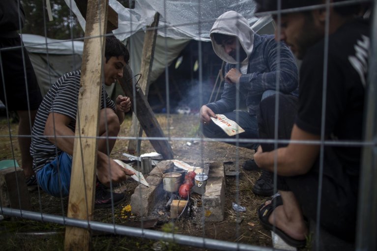 Sur cette photo d'archives prise en août 2021, des migrants préparent de la nourriture dans le camp de migrants construit sur un terrain d'entraînement militaire de Rudninkai, à environ 38 kilomètres au sud de Vilnius, en Lituanie. Crédit : AP