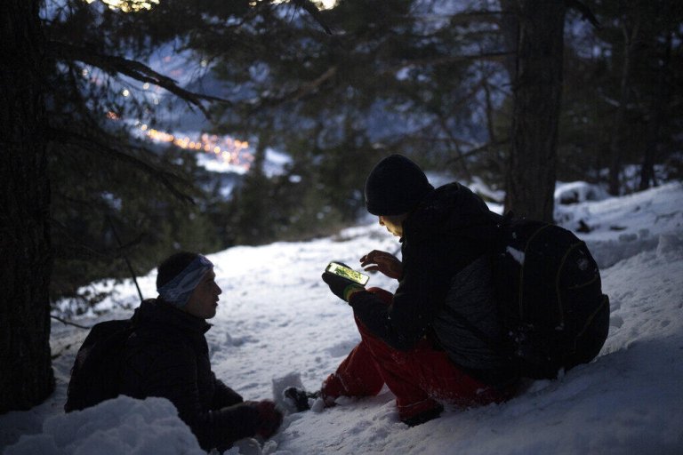 Un migrant afghan, regarde une carte sur son téléphone alors qu'il traverse les Alpes franco-italiennes, en décembre 2021. (Image d'illustration) Crédit : AP
